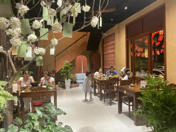 Không gian bàn gỗ và cây xanh trong nhà hàng